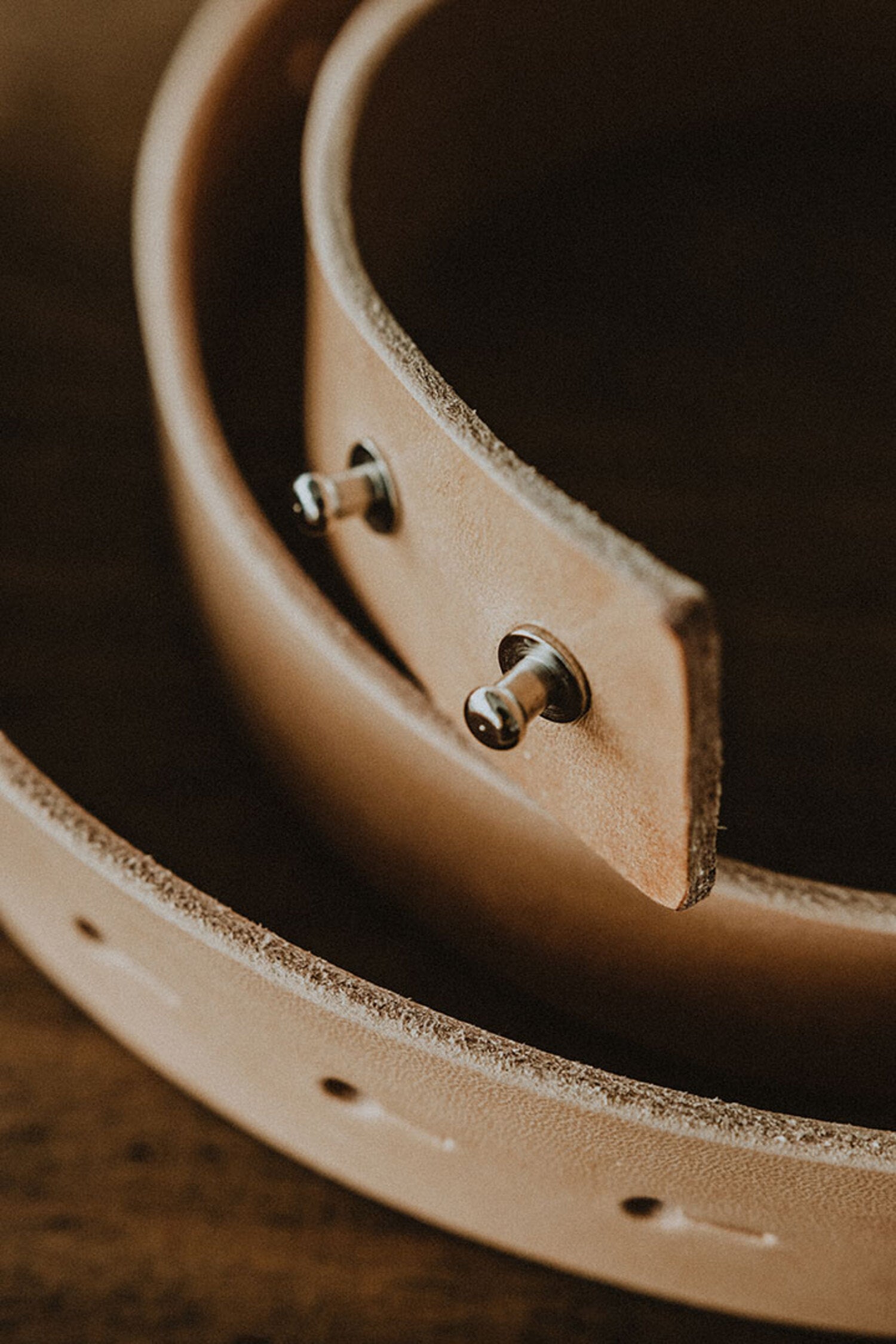 Close-up detail of the Lobo leather belt metal pin fastening system, highlighting the handcrafted finish and leather thickness.