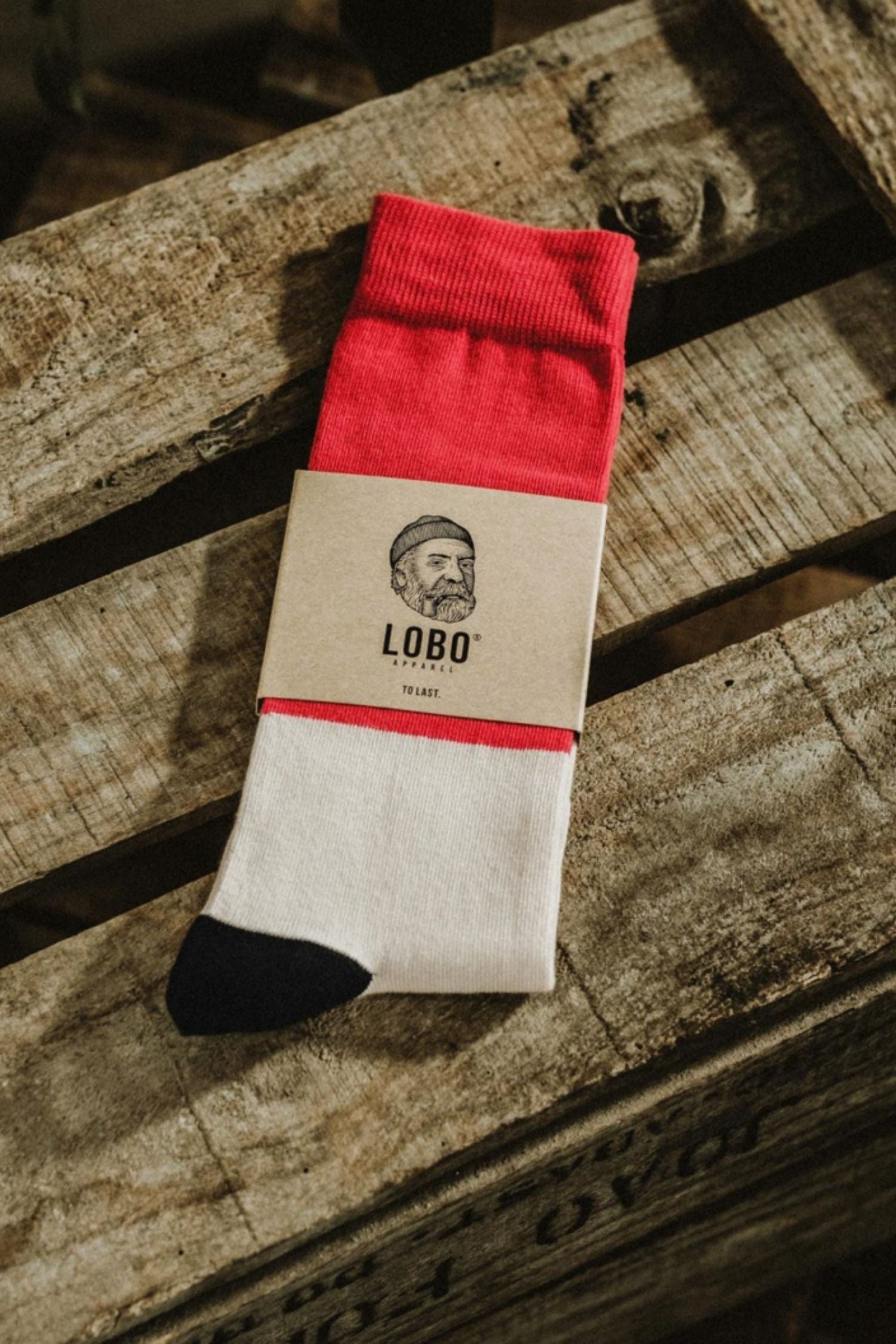 Lobo Classic Red Socks made from premium natural fibers with red, white, and black color blocks, featuring sustainable kraft packaging on wood.