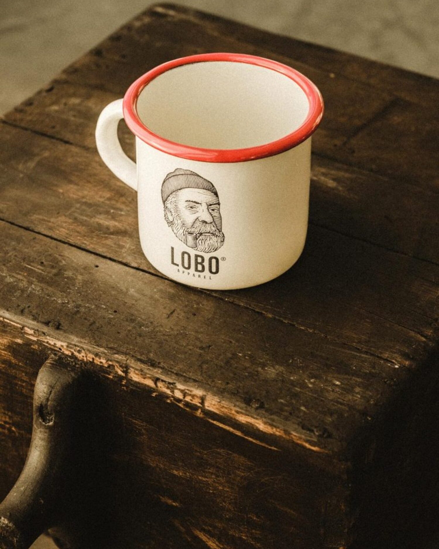 High-angle top view of the LOBO Red Rim mug on rustic wood, showing the white interior and ergonomic handle.