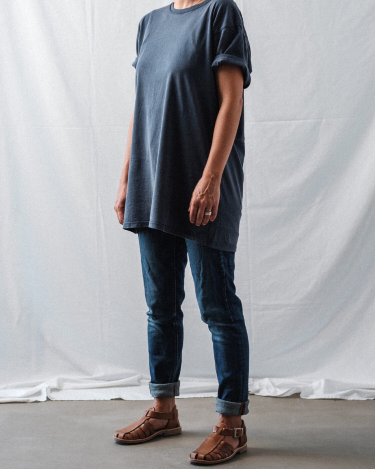 Female model in a casual oversized t-shirt and jeans outfit, wearing brown Lobo Leather Sandals, highlighting the unisex and timeless style