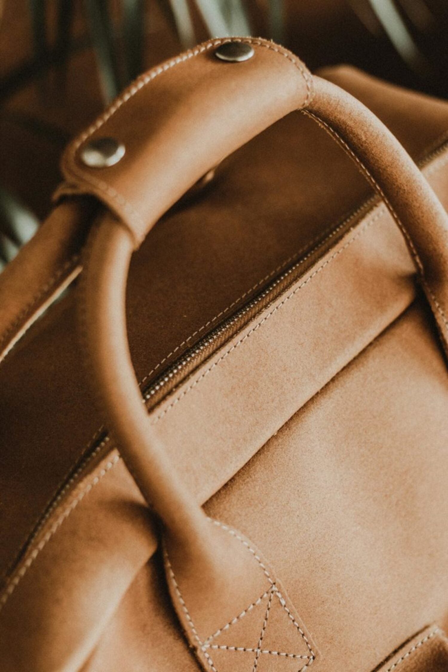 lose-up of the handle and handcrafted stitching on the Lobo Leather Suitcase, showcasing the premium full-grain leather texture and quality.
