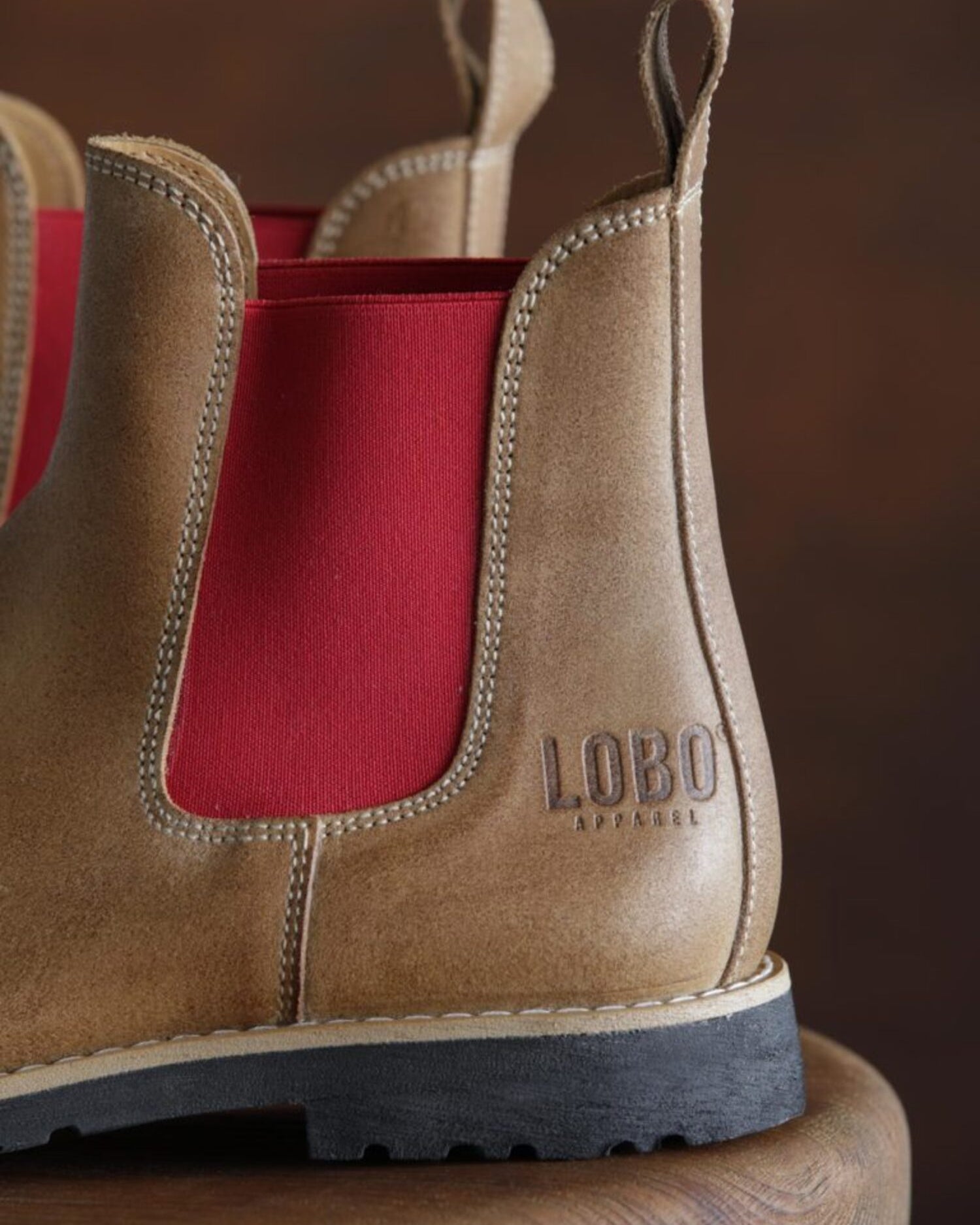 Close-up of the heel of Lobo tan leather boots with the stamped logo and vibrant red side panel.