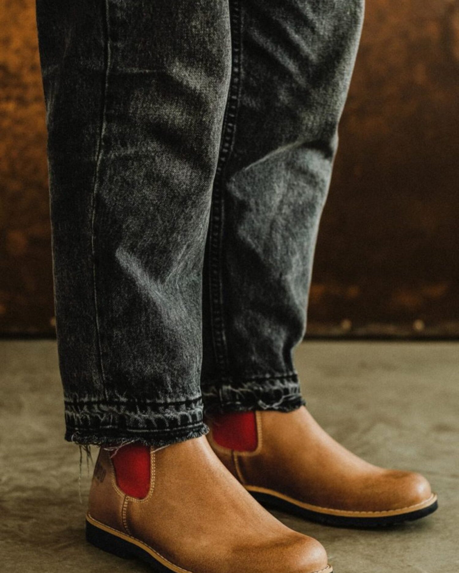 Close-up of Lobo Red Elastic leather boots with distinct red side panels, paired with dark wash jeans.