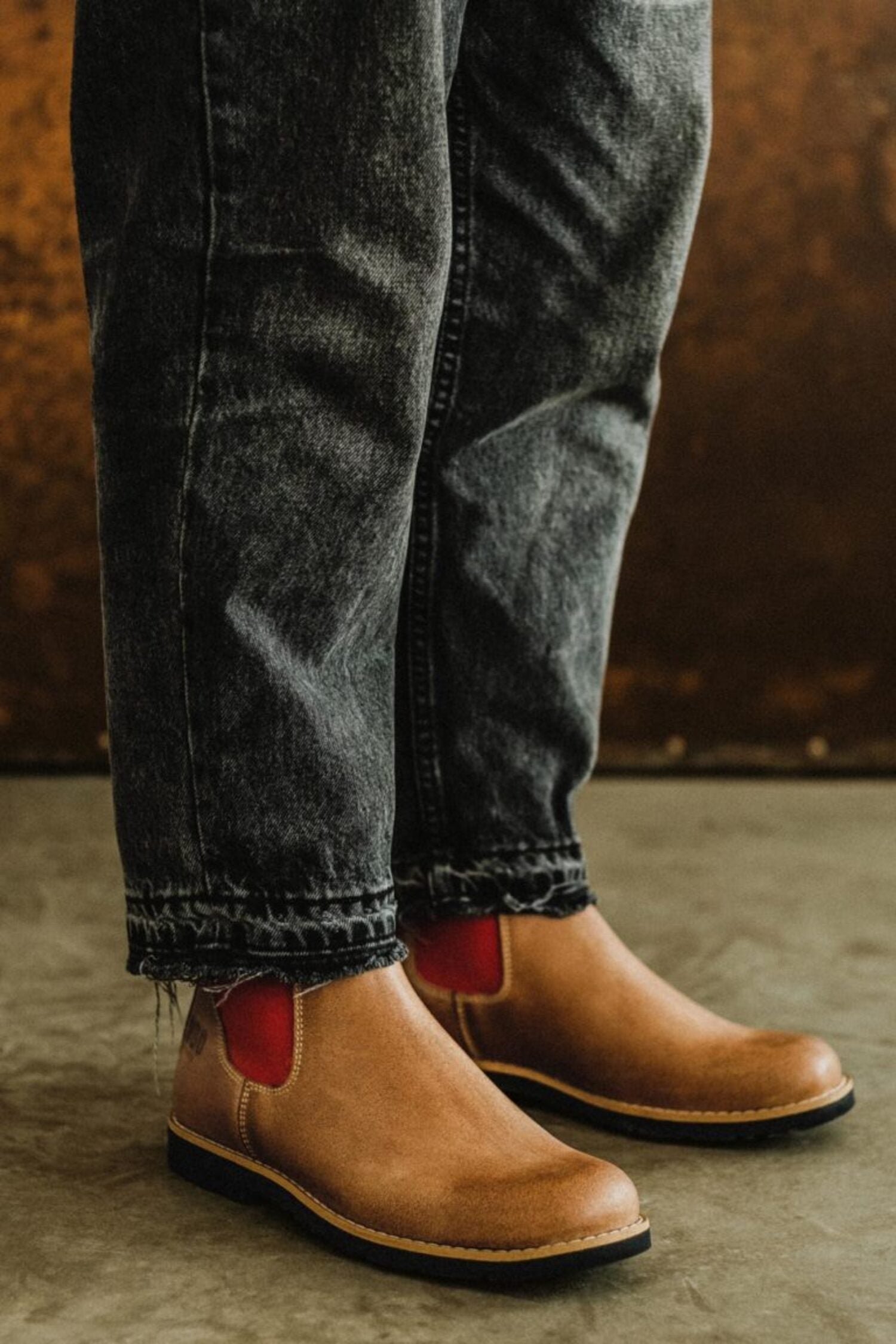 Close-up of Lobo Red Elastic leather boots with distinct red side panels, paired with dark wash jeans.