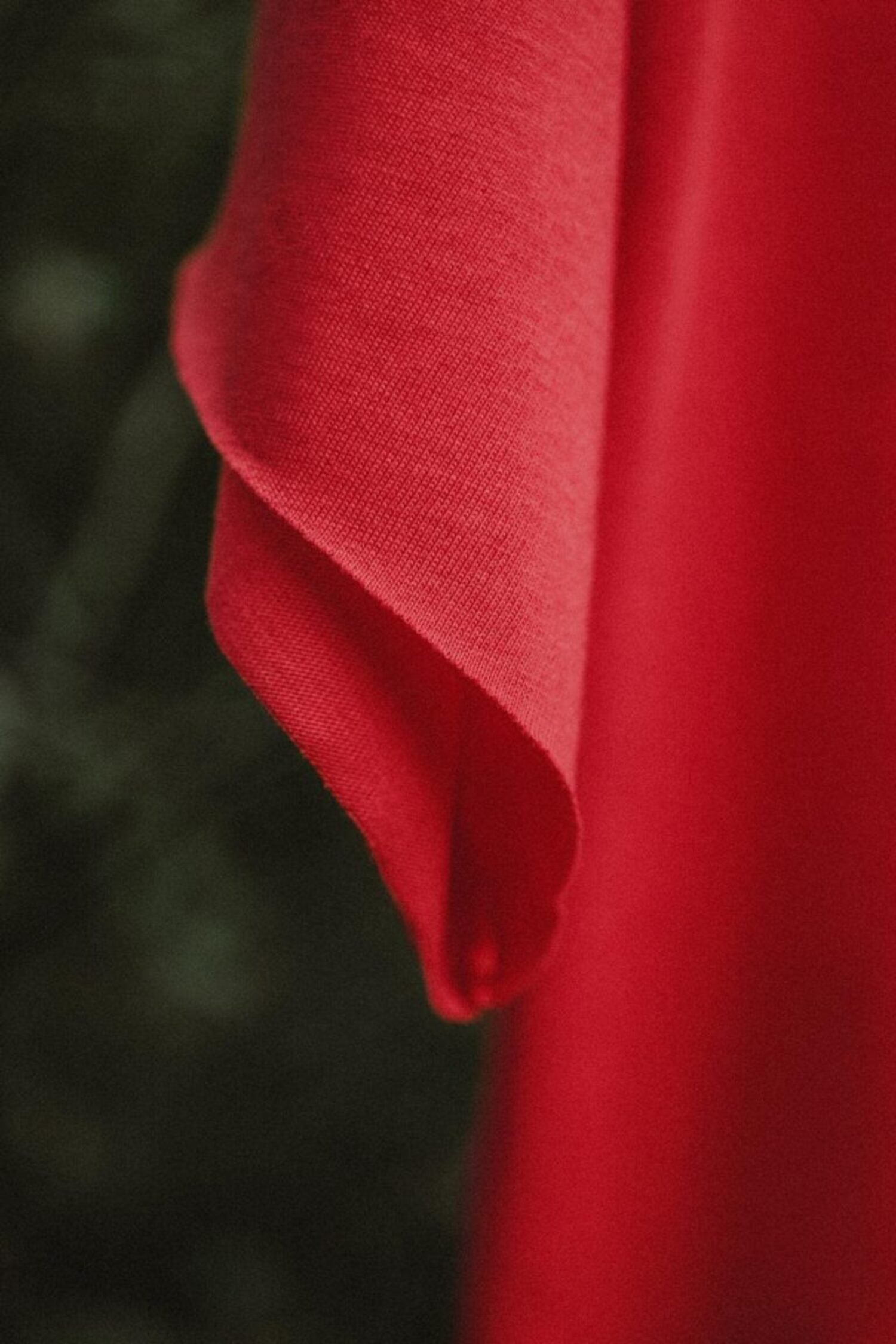 Close-up of a red high-quality cotton t-shirt sleeve, highlighting the fabric texture and durable stitching.