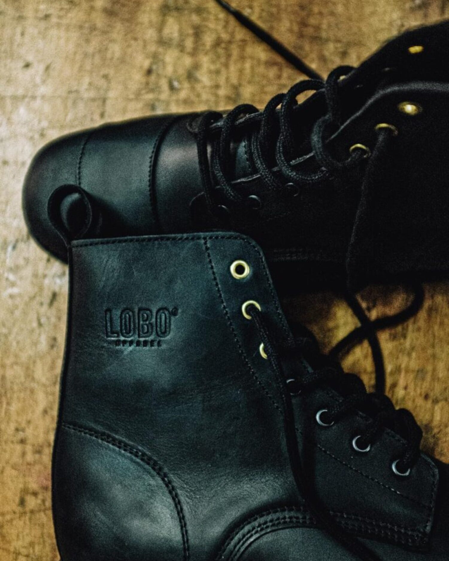 Side detail of the black leather Lobo Tigre boots, showcasing the embossed Lobo logo and decorative golden eyelets.
