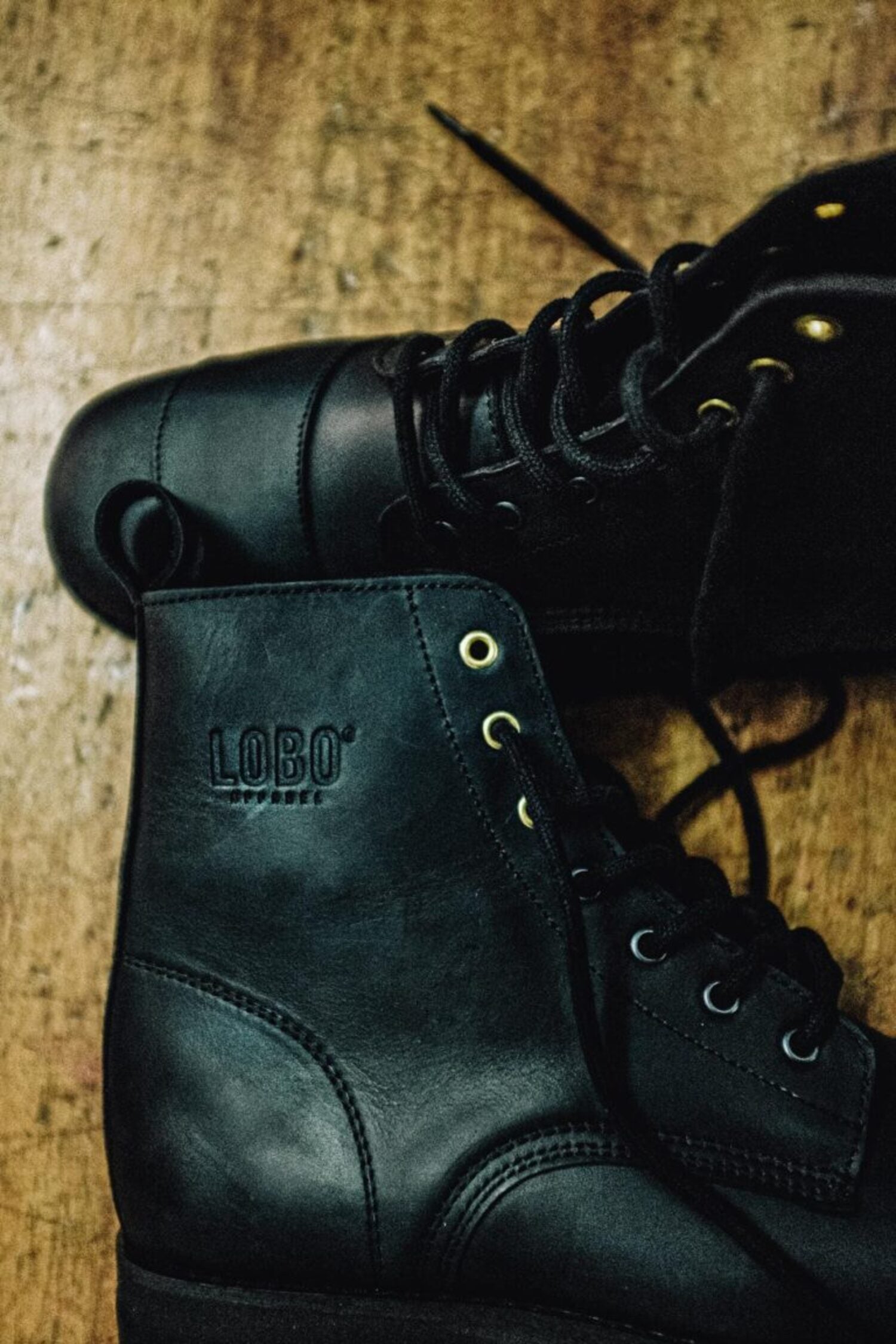 Side detail of the black leather Lobo Tigre boots, showcasing the embossed Lobo logo and decorative golden eyelets.