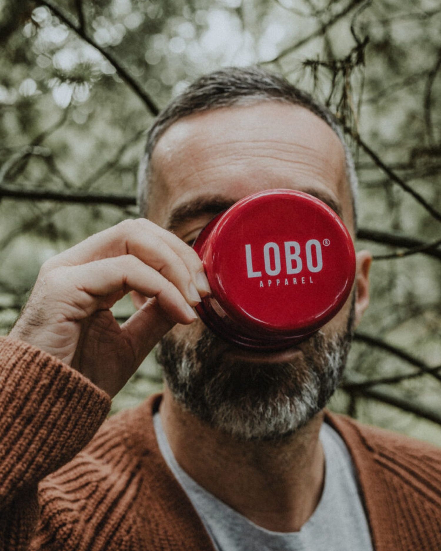 Close-up of the bottom of the red enamel mug featuring the Lobo Apparel logo in white.