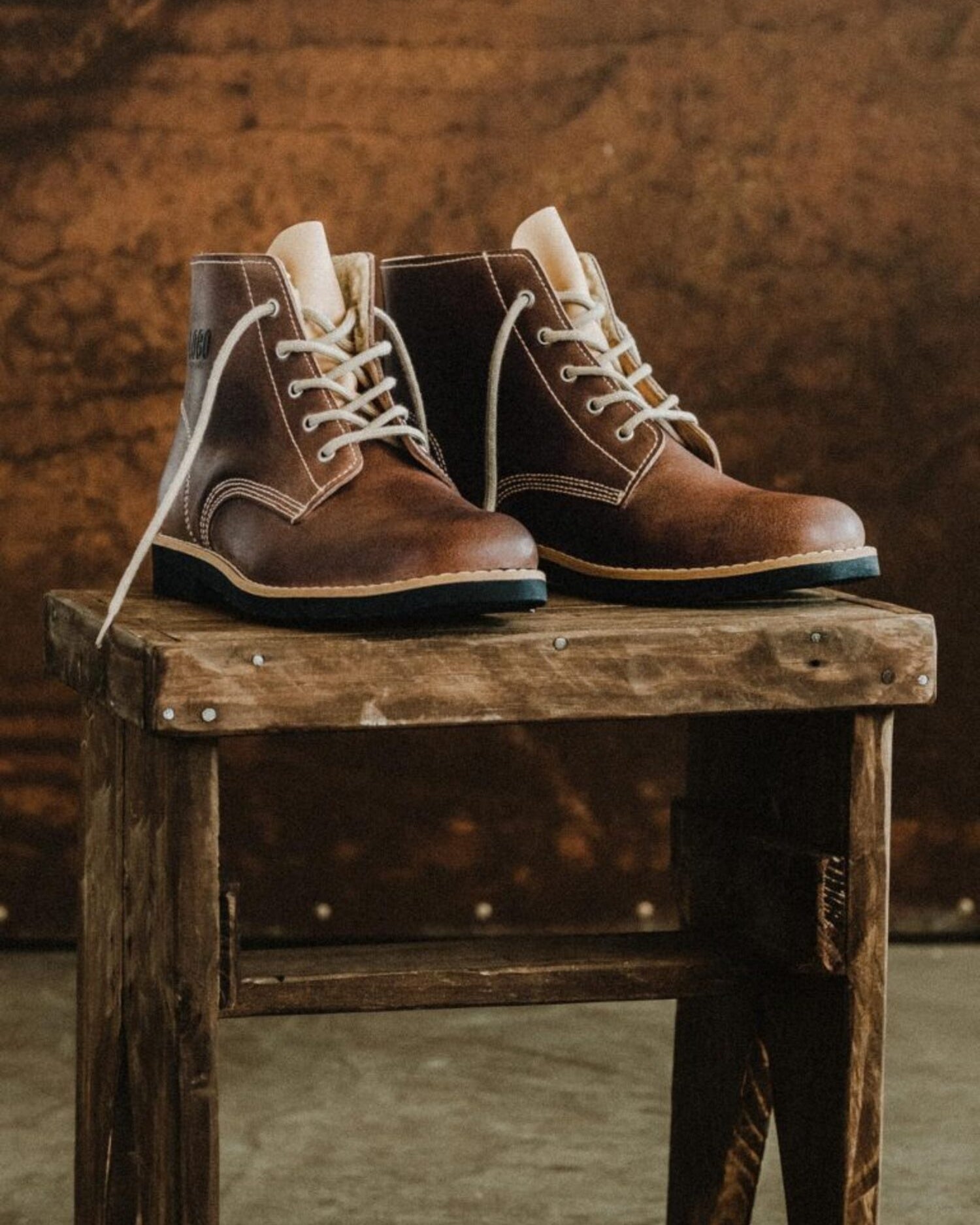 Lobo Warm Boots in premium leather with cream lace option on a rustic stand.