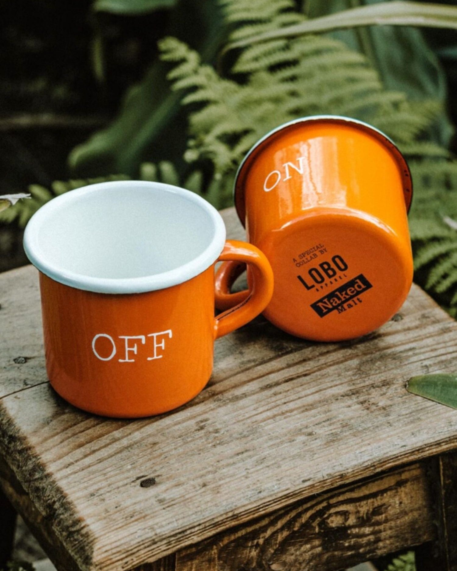 Close-up of the Lobo x Naked Malt mug base showing the collaboration logos and the white ON design on orange enamel.
