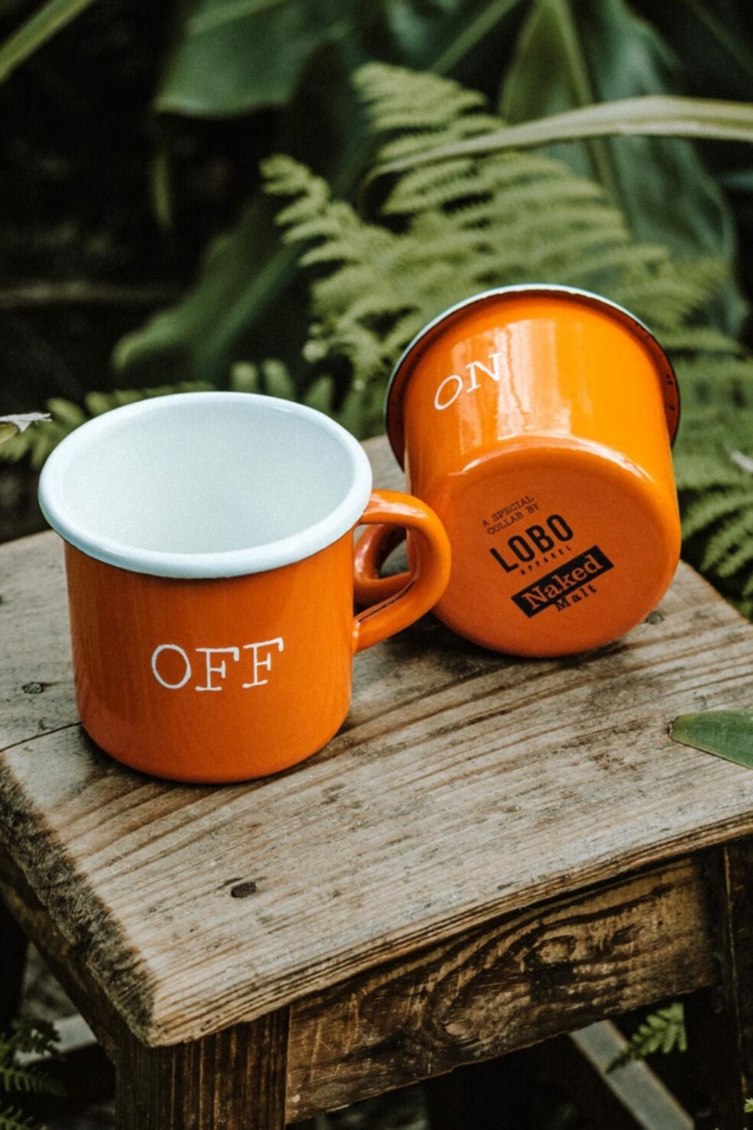 Close-up of the Lobo x Naked Malt mug base showing the collaboration logos and the white ON design on orange enamel.