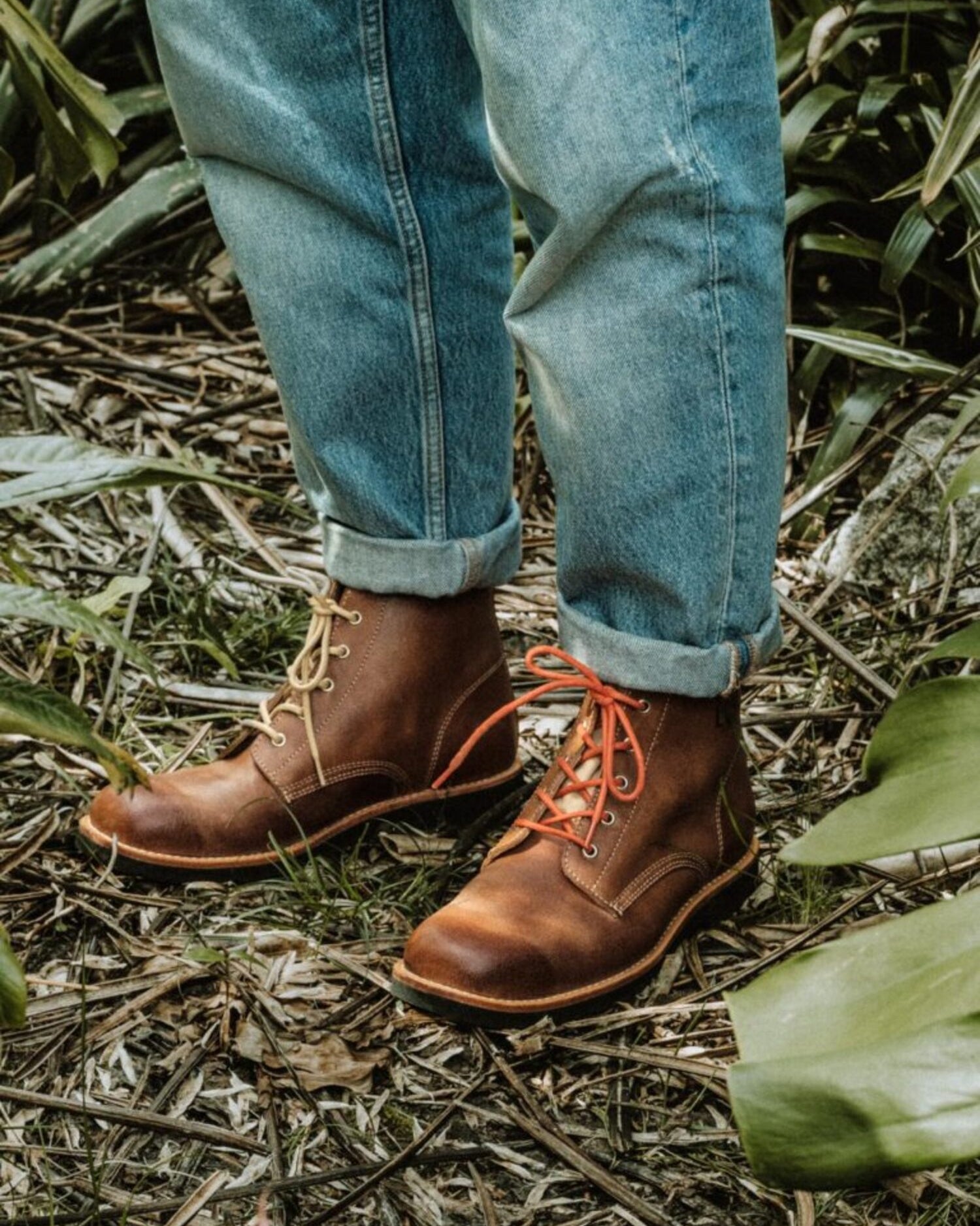 Traditional Portuguese-inspired Lobo Apparel boots worn with denim jeans, featuring orange and cream cotton laces.