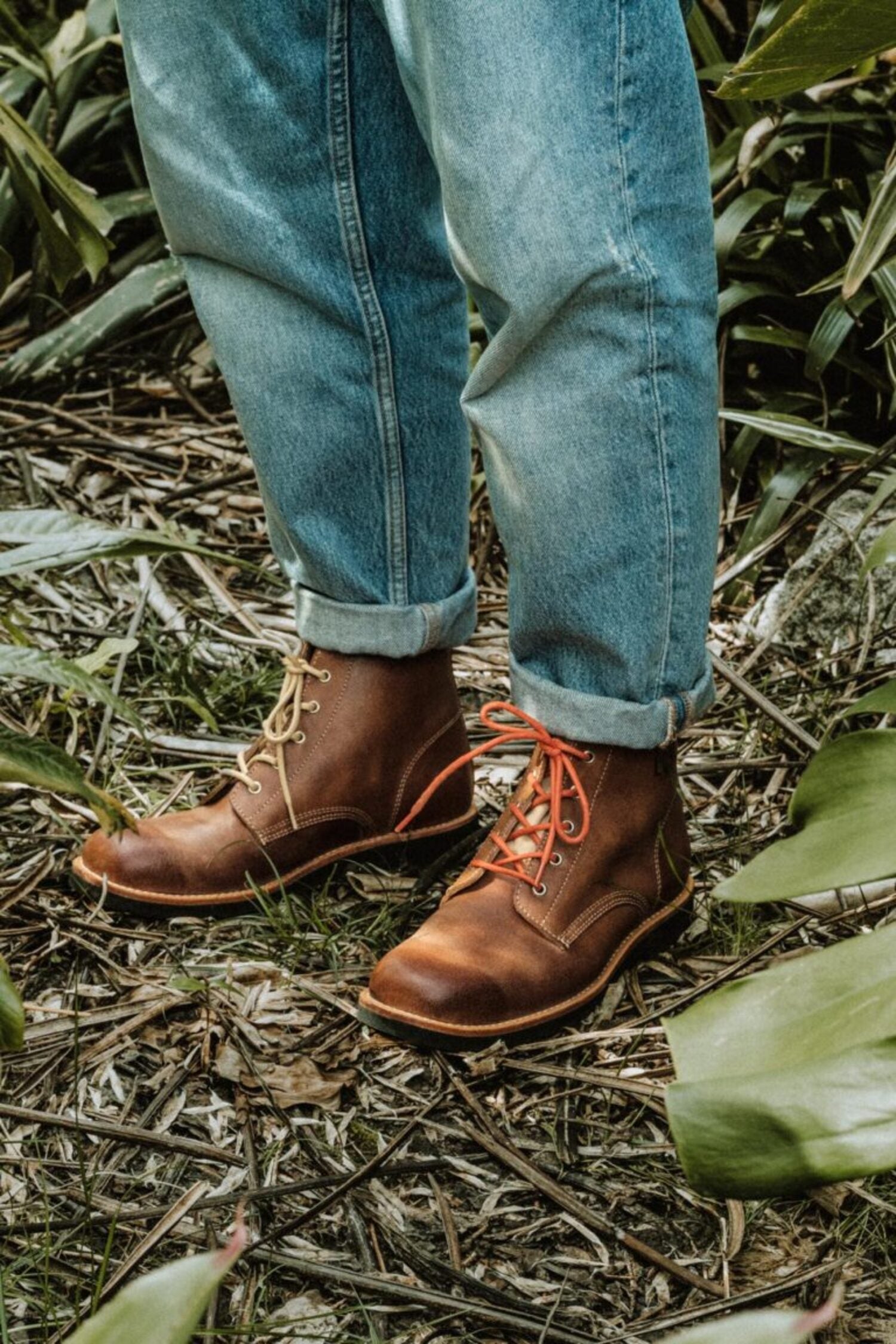 Traditional Portuguese-inspired Lobo Apparel boots worn with denim jeans, featuring orange and cream cotton laces.