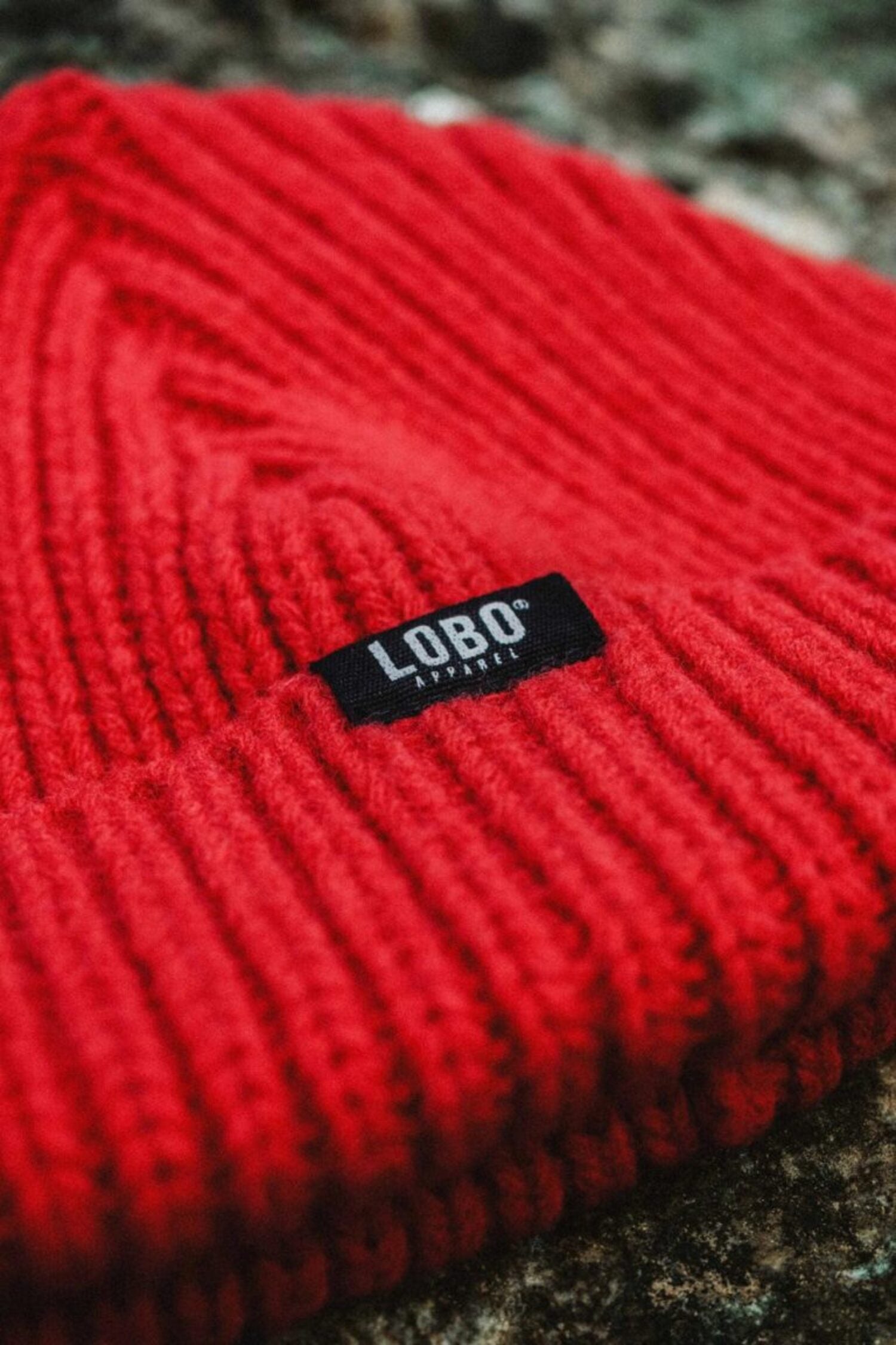 Close-up of the ribbed knit on the Manuel Red Beanie, highlighting the black "LOBO Apparel" label.