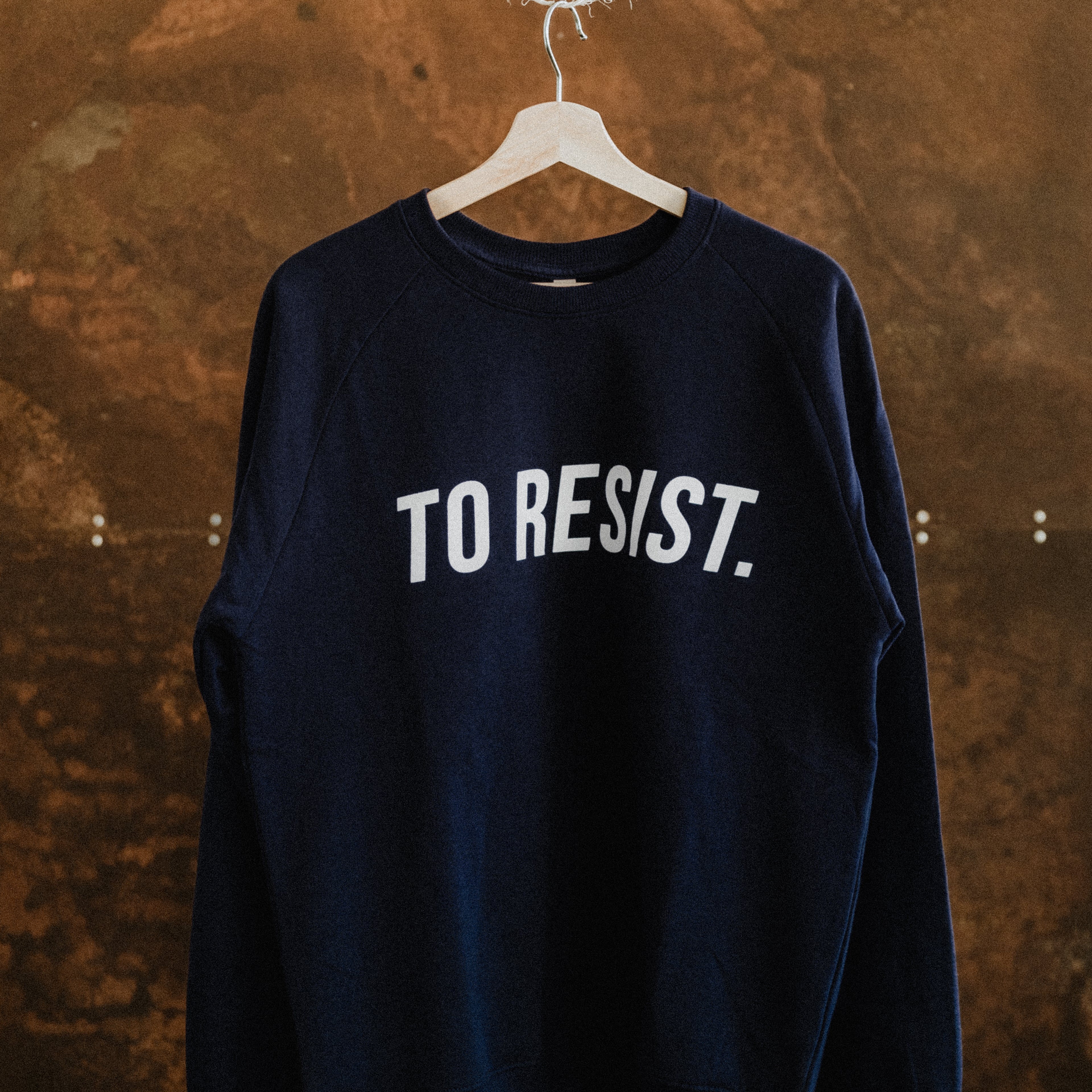 Dark blue unisex sweatshirt featuring the "TO RESIST" white print by Portuguese clothing brand Lobo Apparel, showcasing urban sustainable fashion.