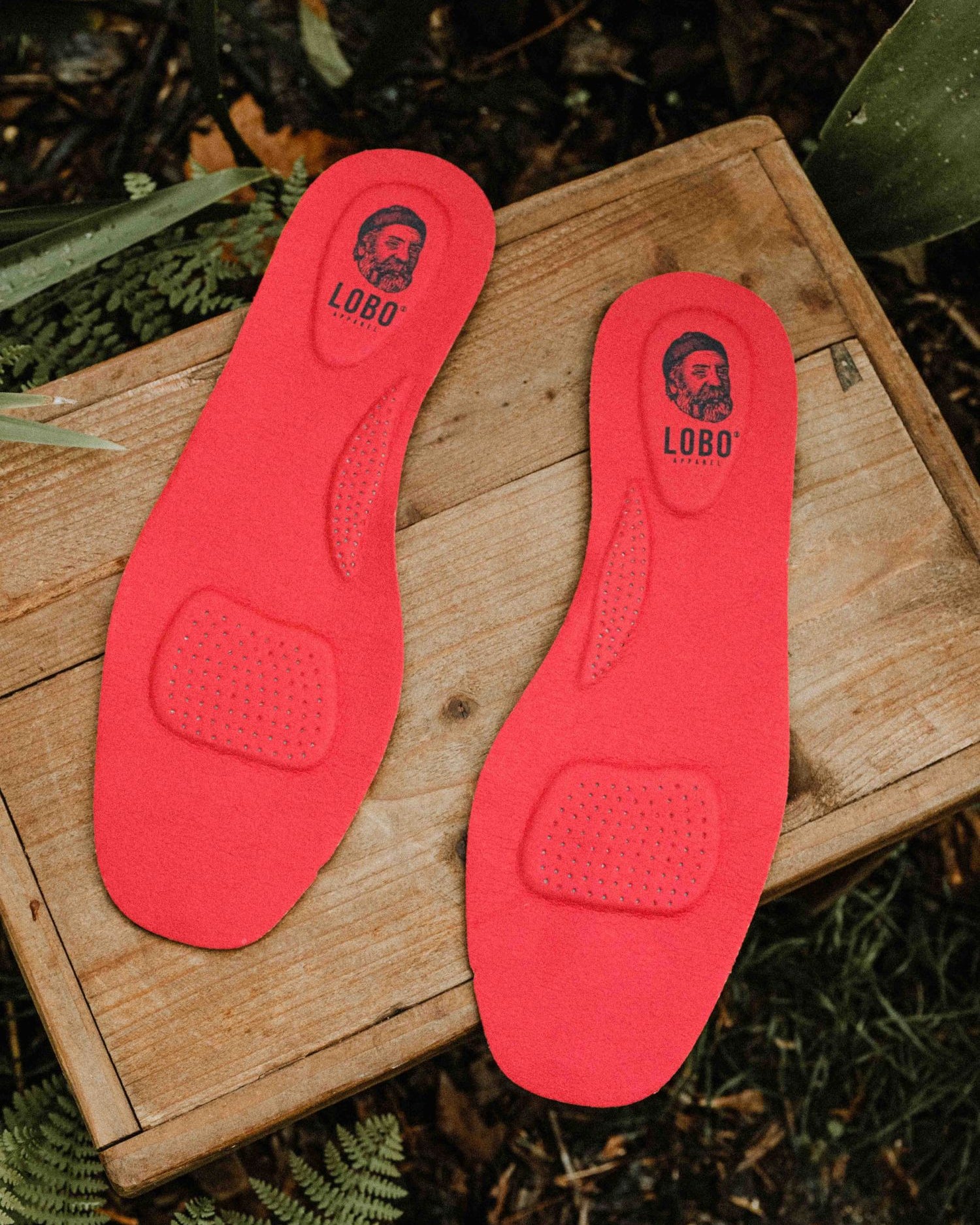 Lobo Insoles insoles on a wooden box, showing the red leather upper and the underside of the insole.