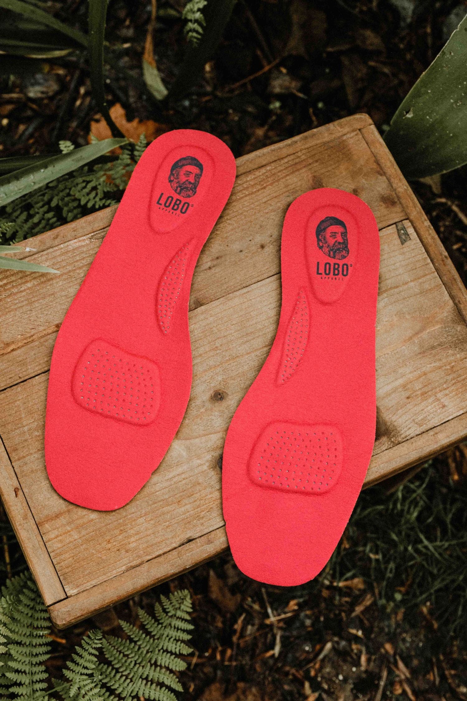 Lobo Insoles insoles on a wooden box, showing the red leather upper and the underside of the insole.