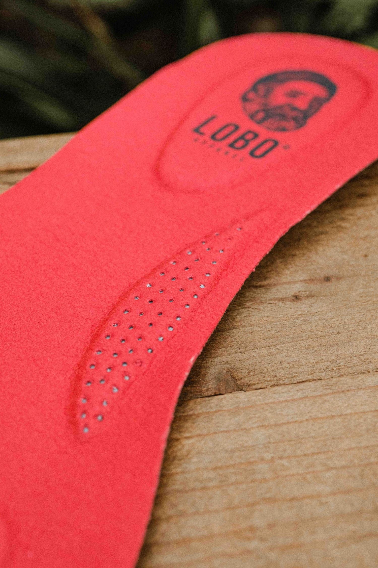 Top view of two red Lobo Insoles leather insoles with visible logo on a wooden box.