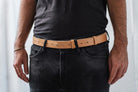 Frontal close-up of Lobo Apparel natural leather belt fastened at the waist, with visible pin closure over black trousers.