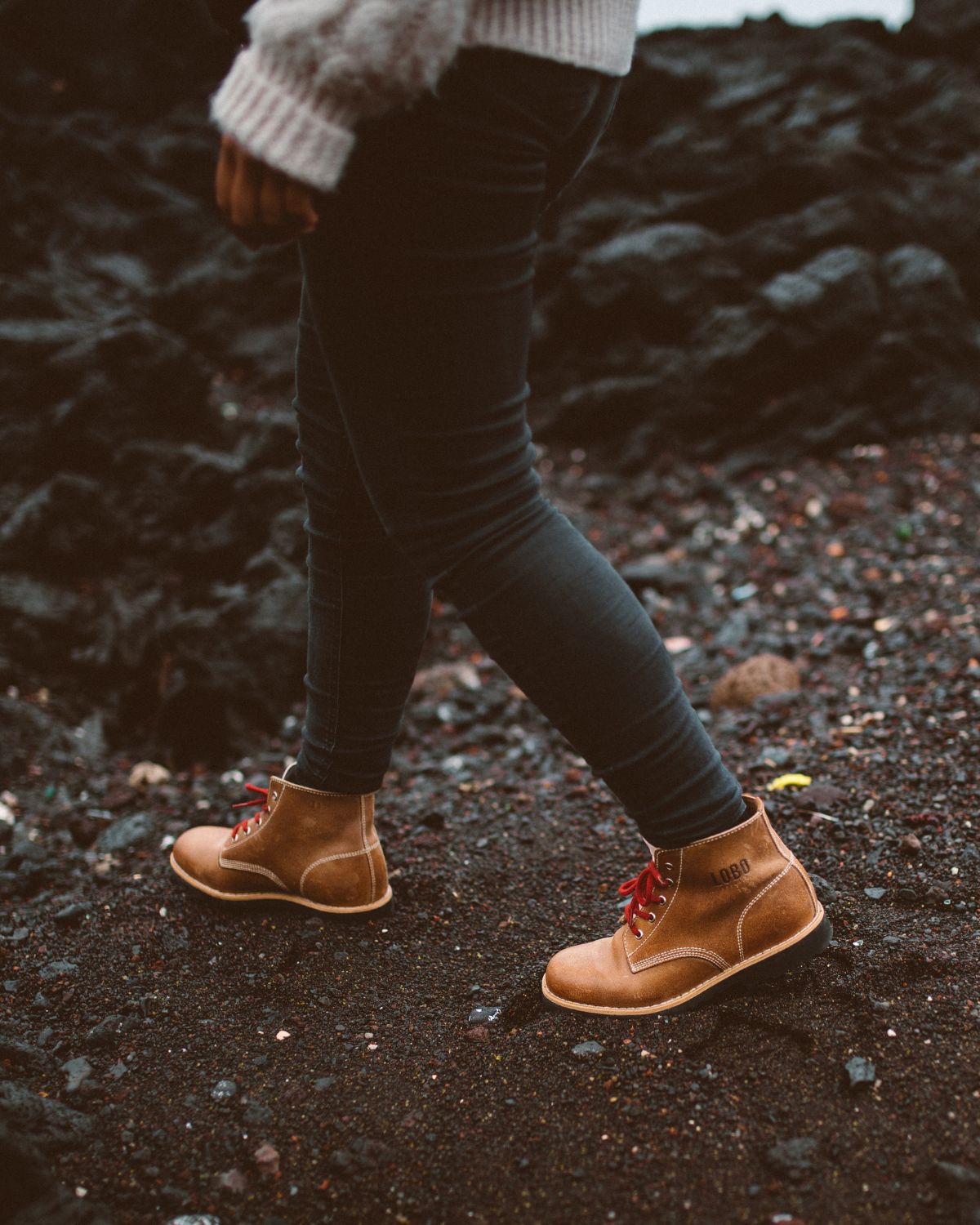 Close-up of Lobo Raw Boots in camel leather with red laces, in motion on volcanic soil in the Azores.