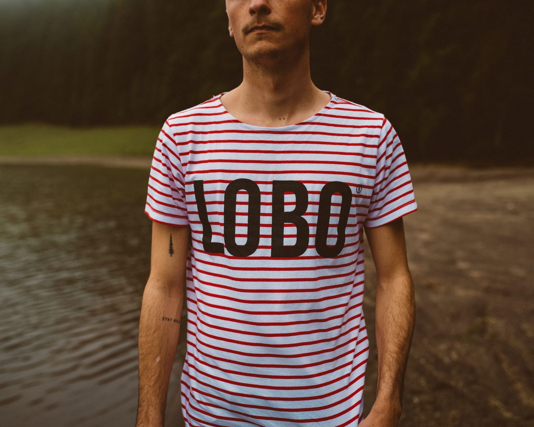 Man wearing a Lobo white and red striped t-shirt with front logo by Lagoa de São Brás.