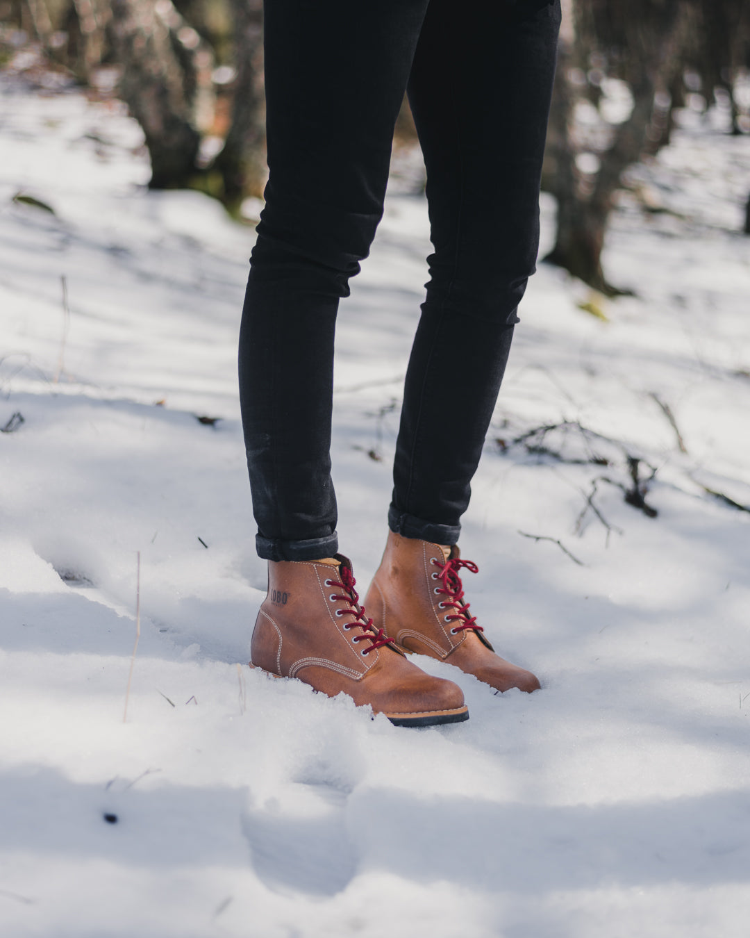 Lobo Raw leather boots showcased in deep snow, highlighting water resistance and traction in harsh winter conditions.
