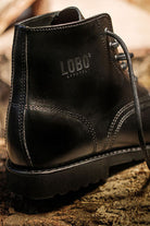 Close-up of the Lobo Apparel logo stamped on the black leather of All Black boots, showing stitching.