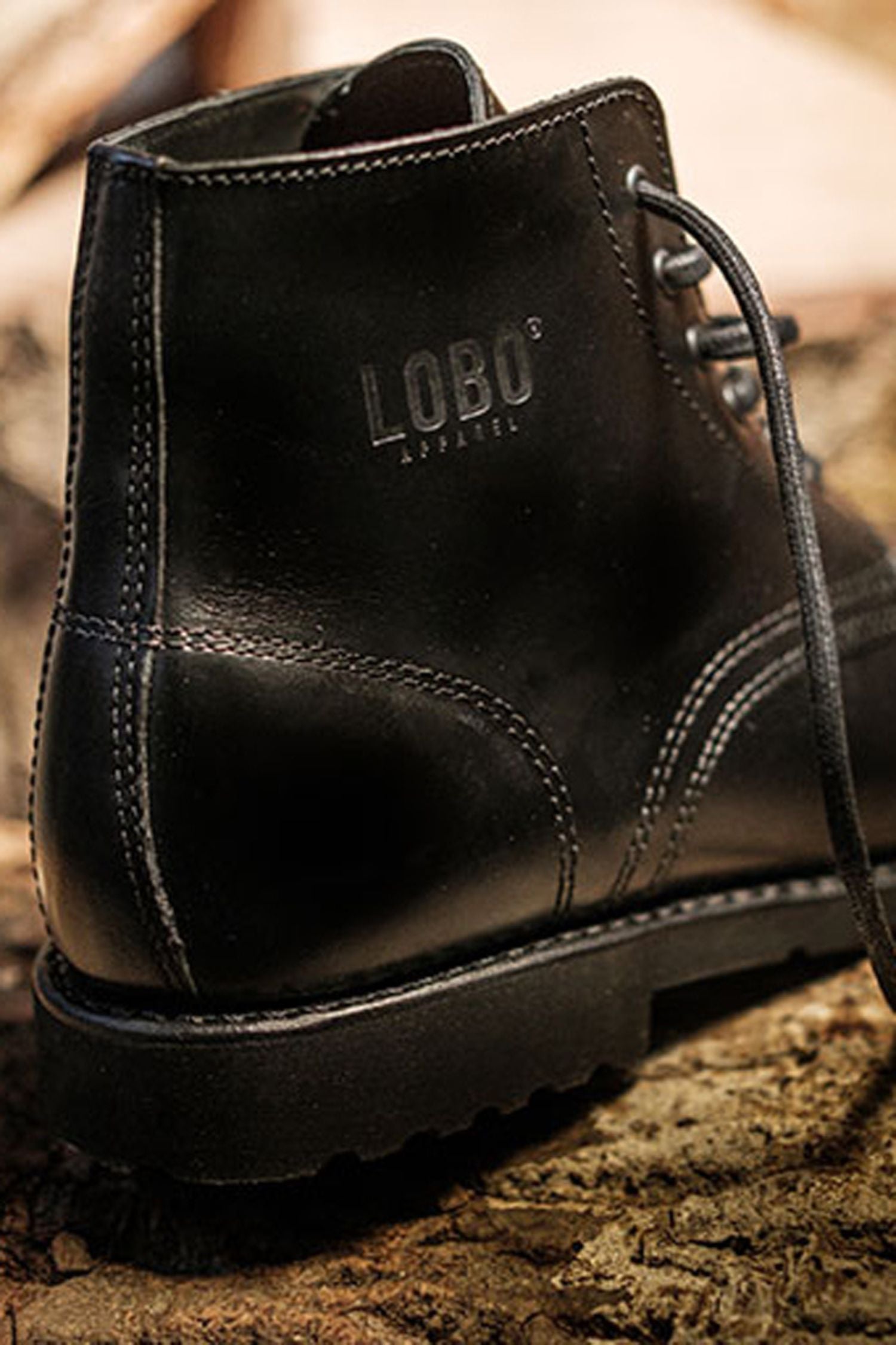 Close-up of the Lobo Apparel logo stamped on the black leather of All Black boots, showing stitching.