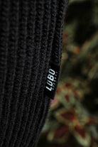 Close-up of the black knit fabric of the Lobo Black Wool Cardigan with the Lobo Apparel side label.
