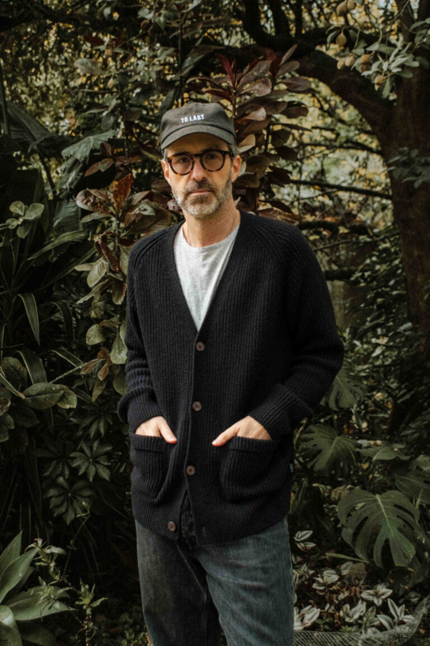 Man wearing the black Lobo Black Wool Cardigan with front buttons and patch pockets.