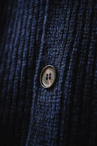Macro shot of the denim blue wool texture and classic button detail of the Lobo Apparel cardigan.