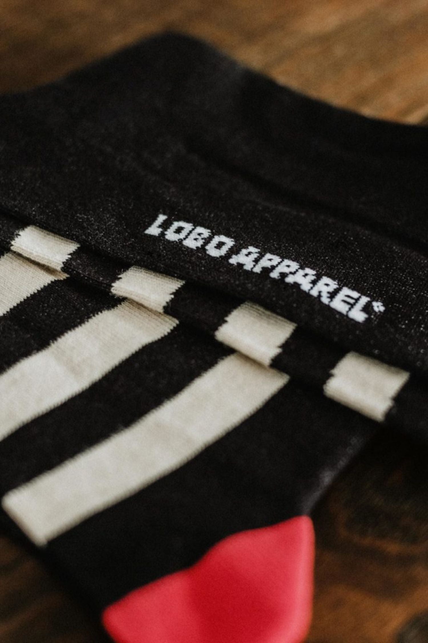 Close-up of the "Lobo Apparel" logo embroidered in white on premium black knit socks.