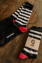 Set of Lobo Black Stripes cotton socks shown both unpacked and packaged, displaying the minimalist striped design.