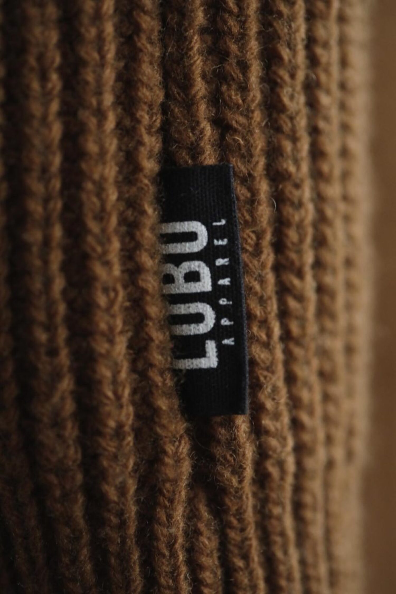 Close-up of the brown wool knit texture and Lobo Apparel black side seam brand tab.