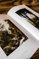 Open pages of the Lobo 'CASA MAIOR' book displaying nature photography of forests and a river, on high-quality paper.