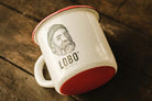 LOBO enamel mug tilted on a wooden table, revealing the vibrant red base and the sturdiness of the material.