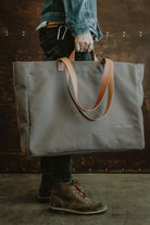 Man holding the Lobo Green Huge Bag in military green canvas with leather handles, showcasing its large size.