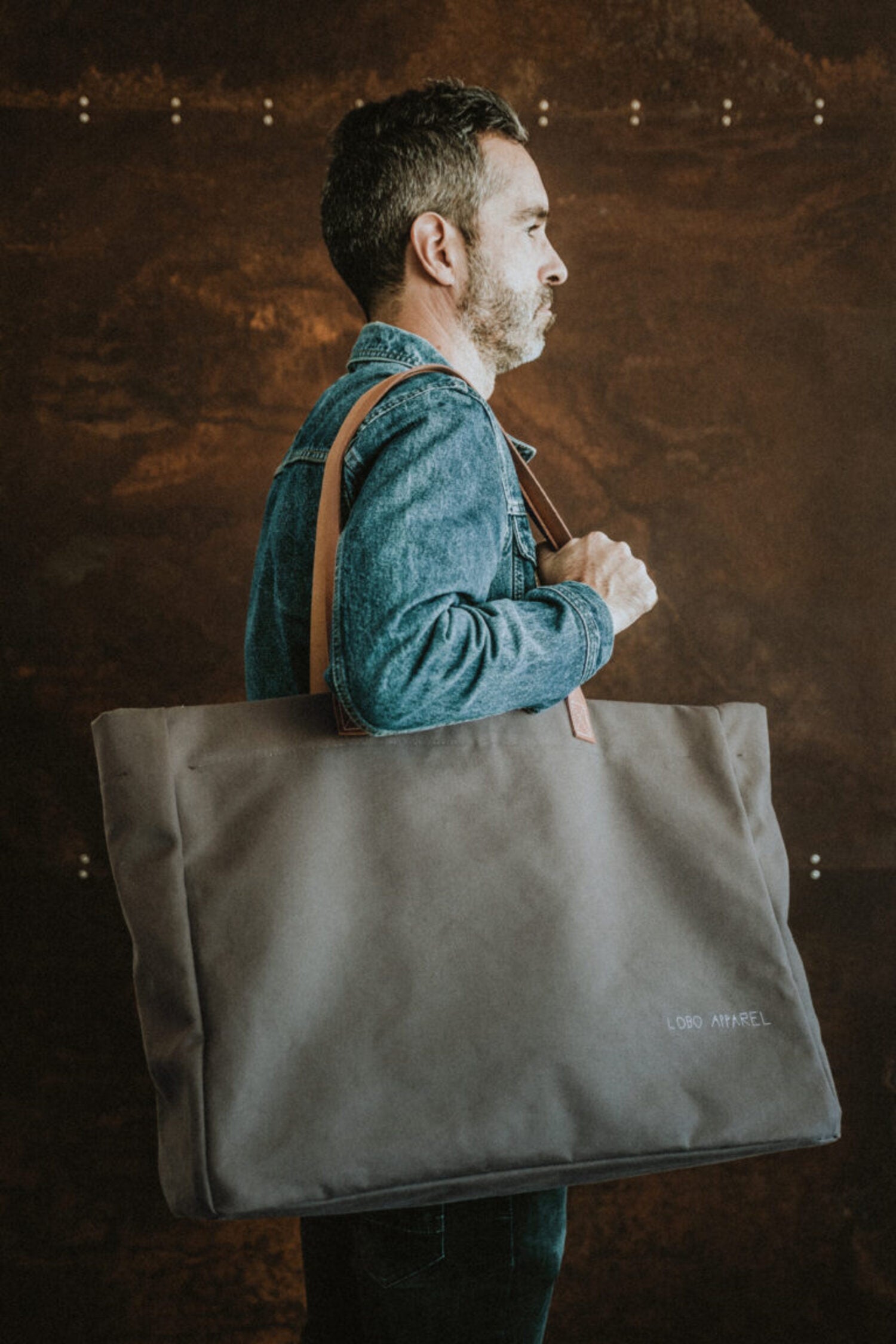 Man carrying the Lobo Green Huge Bag over his shoulder, displaying the functional design and special collaboration with Francisco Cipriano.