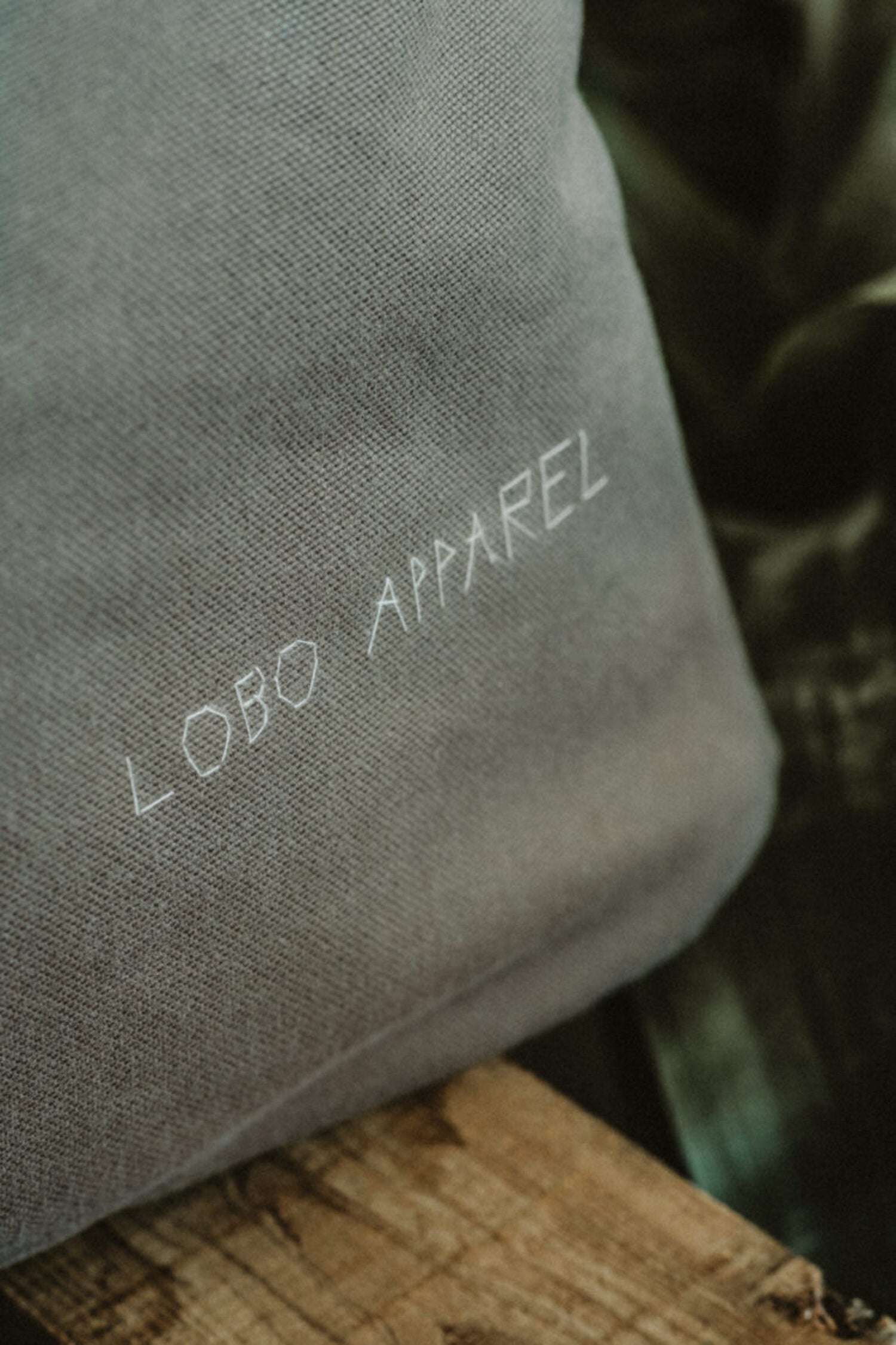 Close-up detail of the LOBO APPAREL name embroidered with light thread on the bag's military green canvas.