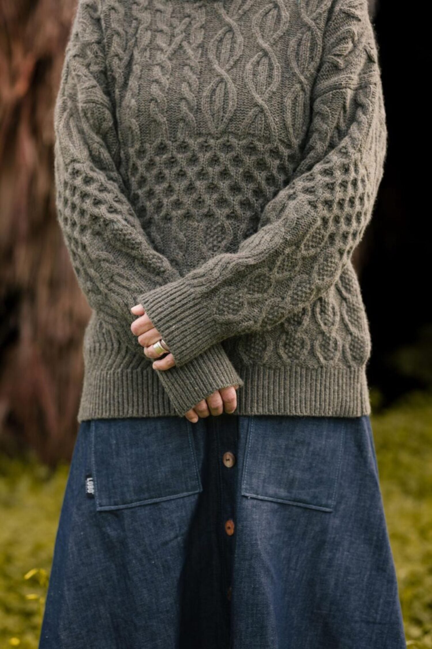Autumn outfit featuring the Lobo Inês denim skirt paired with a chunky grey knit sweater in a natural setting.
