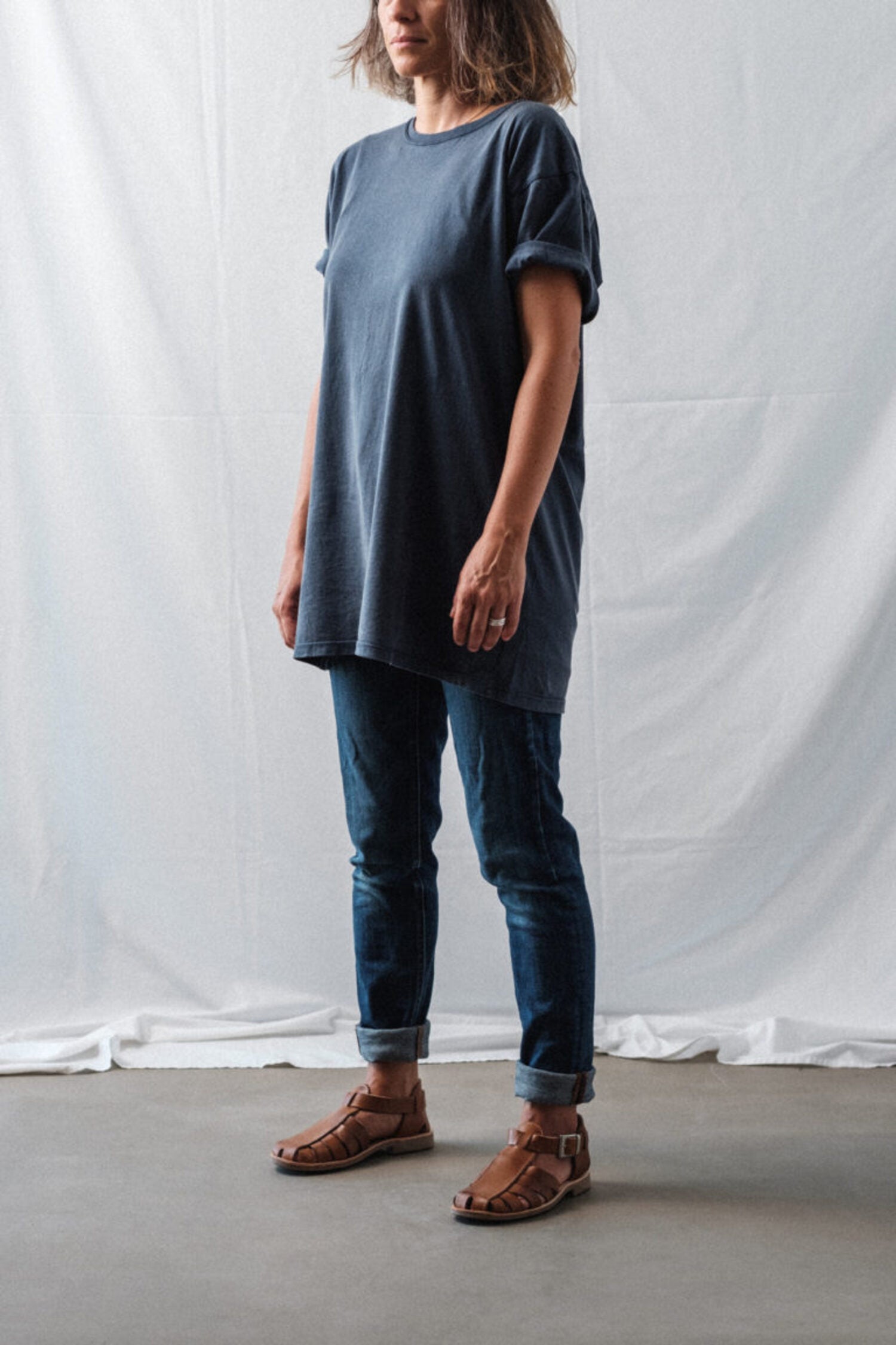 Female model in a casual oversized t-shirt and jeans outfit, wearing brown Lobo Leather Sandals, highlighting the unisex and timeless style