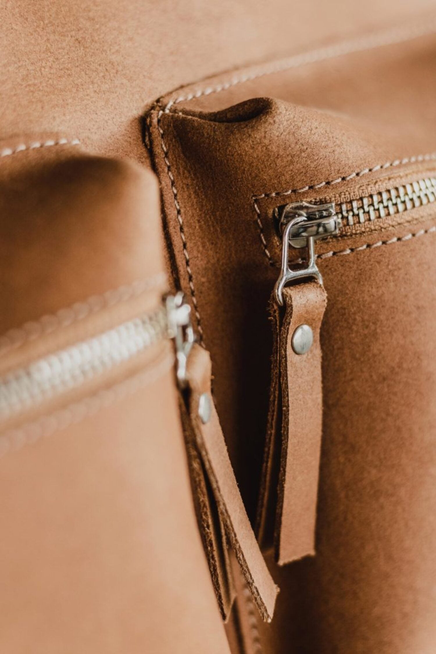 Close-up of the front zippered pockets on the Lobo Leather Suitcase, showcasing the premium leather grain and functional craftsmanship.