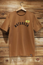 Unisex Lobo "Natureza" t-shirt in brown, hanging on a wooden hanger against a rustic wooden wall.