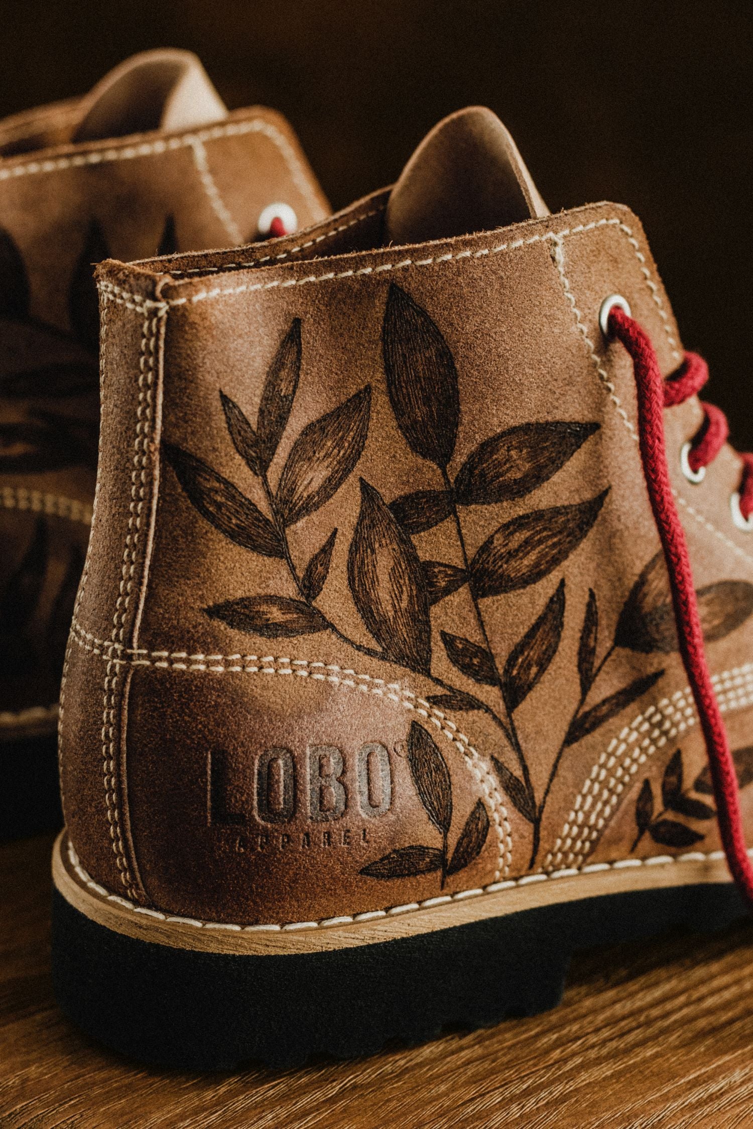 Side detail of the Lobo Raw Boots by Cláudia Salgueiro in brown leather with hand-painted botanical illustrations. Embossed LOBO logo and red laces.