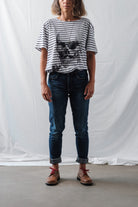 Woman wearing brown Lobo Raw shoes with red laces, styled with dark denim jeans and a striped t-shirt.