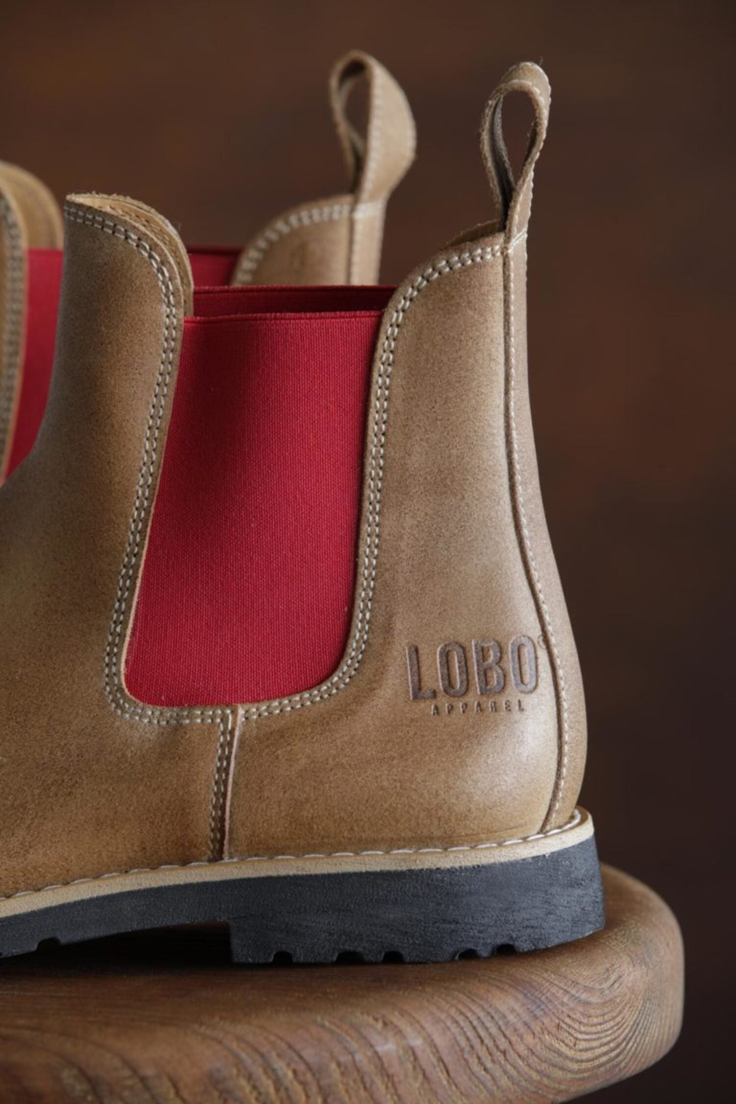 Close-up of the heel of Lobo tan leather boots with the stamped logo and vibrant red side panel.