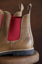 Close-up of the heel of Lobo tan leather boots with the stamped logo and vibrant red side panel.