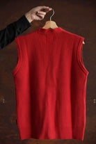 Back view of the red wool Lobo Red Vest hanging on a wooden hanger, highlighting the continuous ribbed knit and the unisex cut.