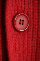Close-up of a red button on the Lobo Red Vest wool vest, highlighting the ribbed knit detail and handcrafted finish.