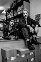 Black and white portrait of the Lobo x Casa Tigre collaborators in a workshop setting, surrounded by shoe boxes and the limited edition boots.